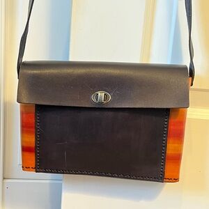 Solid leather black shoulder with orange stripe sides. Simple, elegant design!